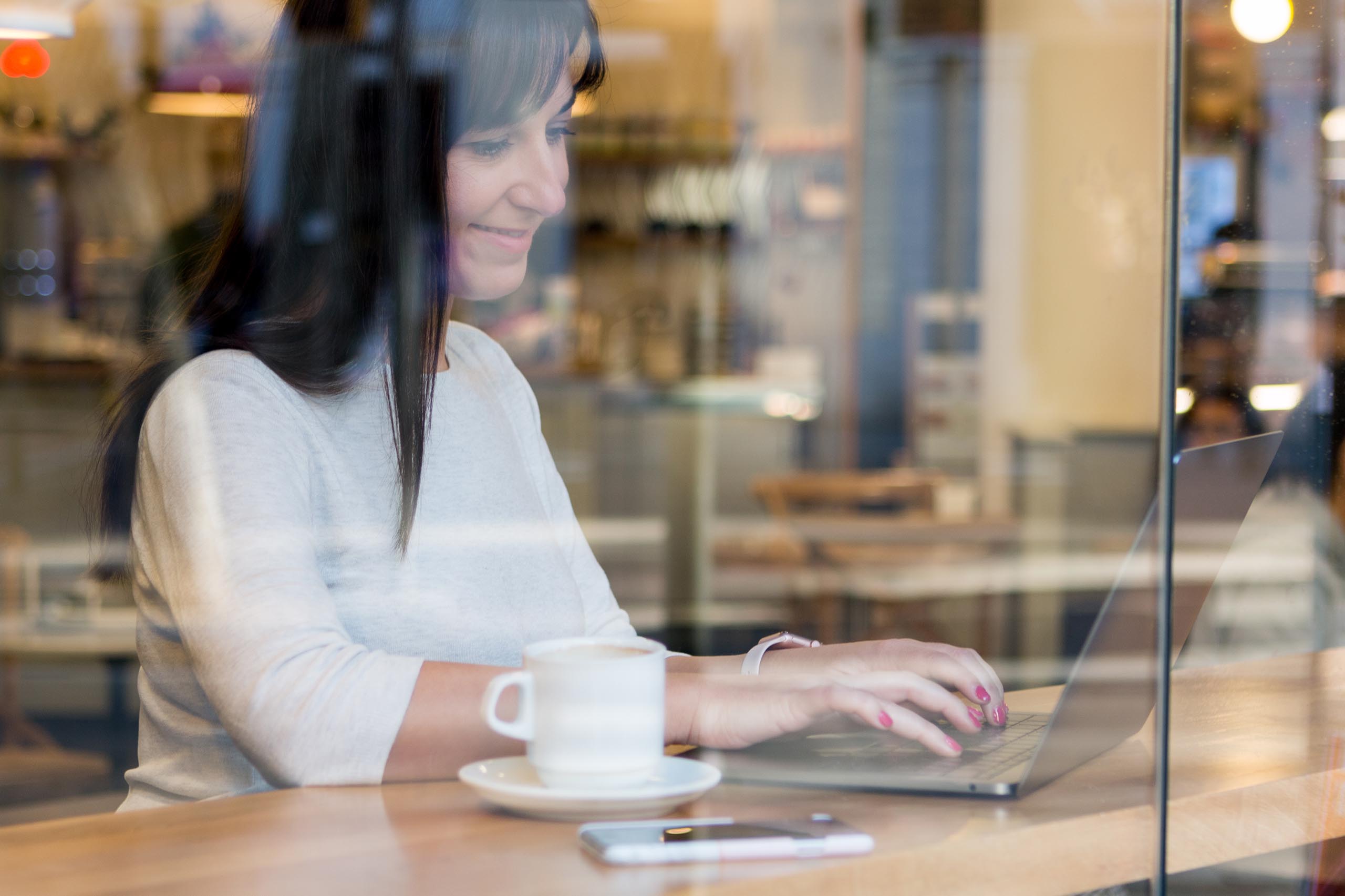 Chica freelance trabajando con un ordenador portátil en una cafetería